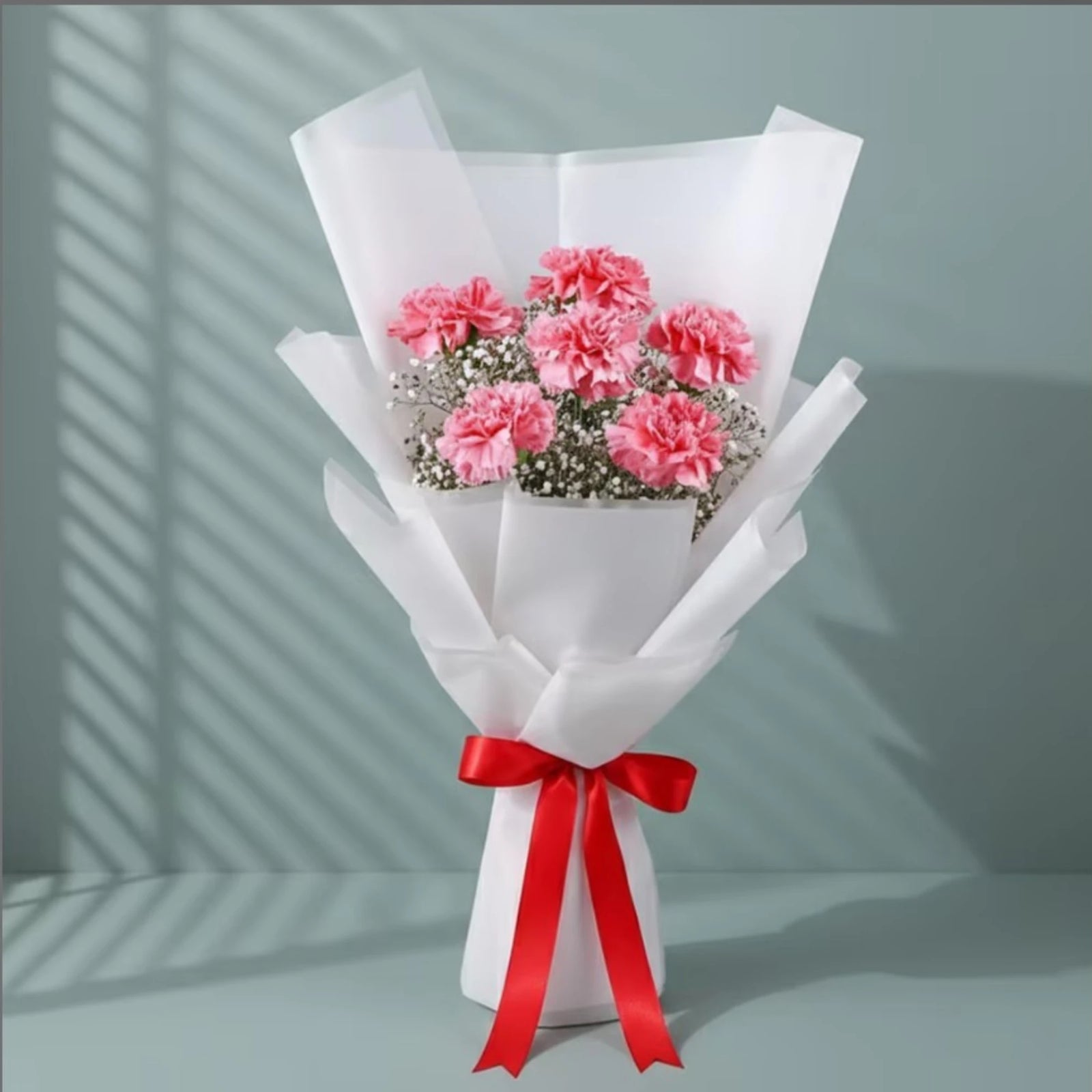 Pink carnations flower bouquet with white baby's breath wrapped in white paper