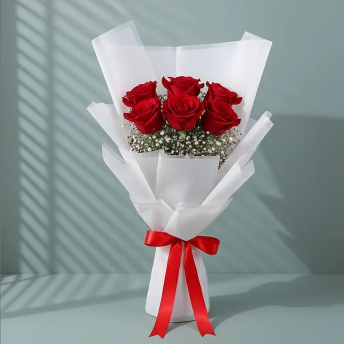 Red roses bouquet wrapped in white paper with red ribbon
