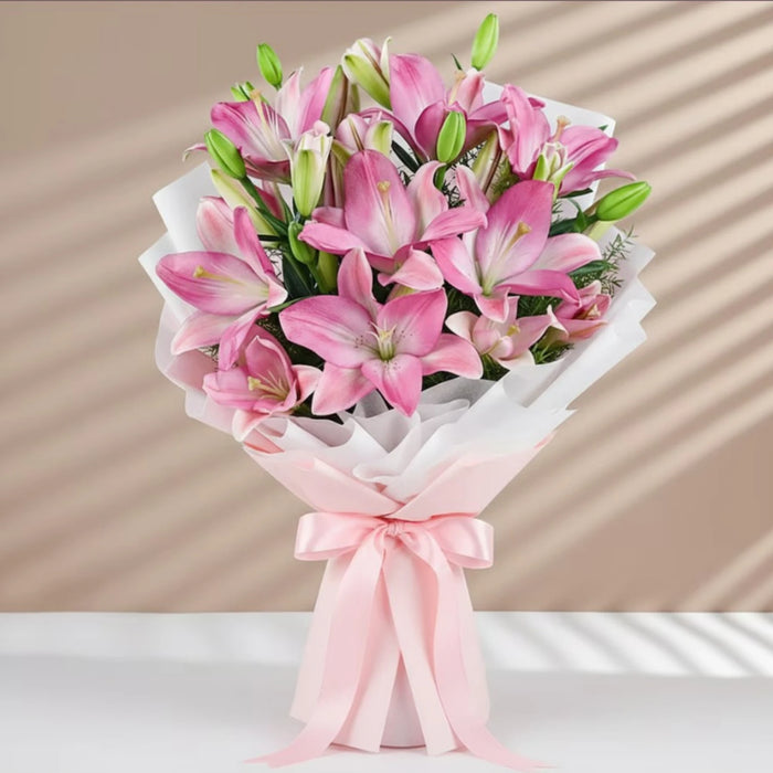 Pink Asiatic lilies bouquet with green buds wrapped in white paper