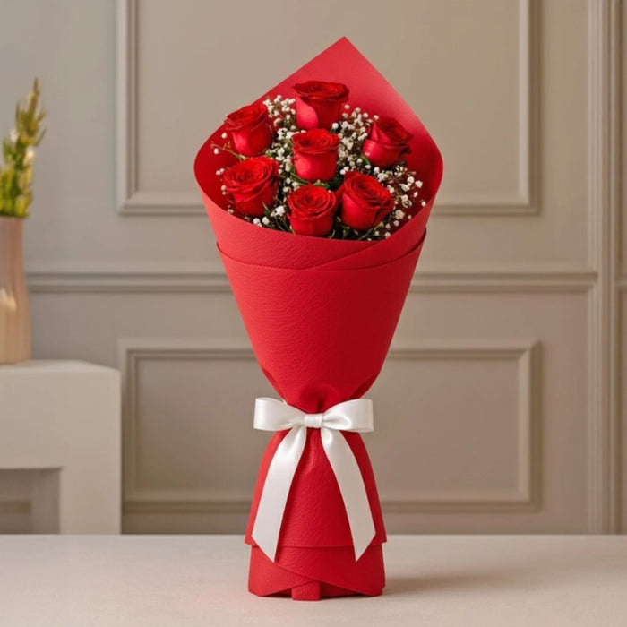 Red roses bouquet wrapped in red paper with white ribbon