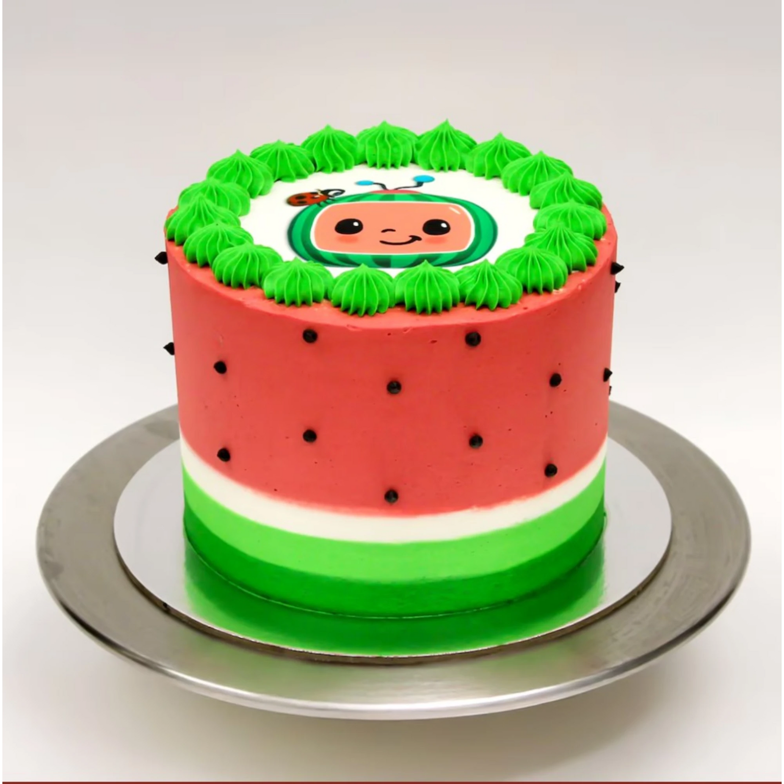 Watermelon-themed birthday cake with green frosting border and cute cartoon watermelon face