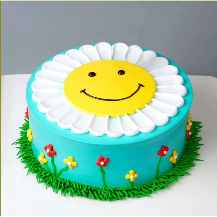 Smiley face cake with flower decorations and green grass border