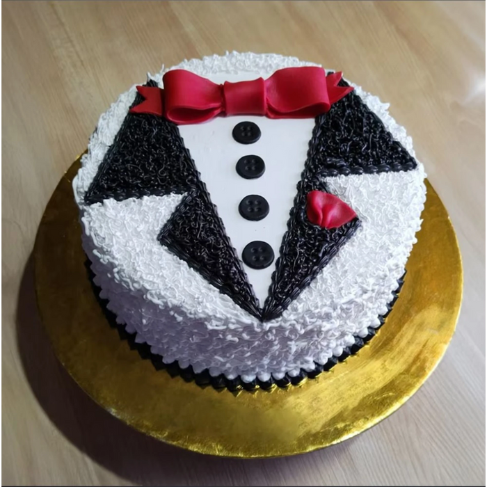 Baby boy birthday cake with tuxedo design, red bow tie, black buttons, and white icing