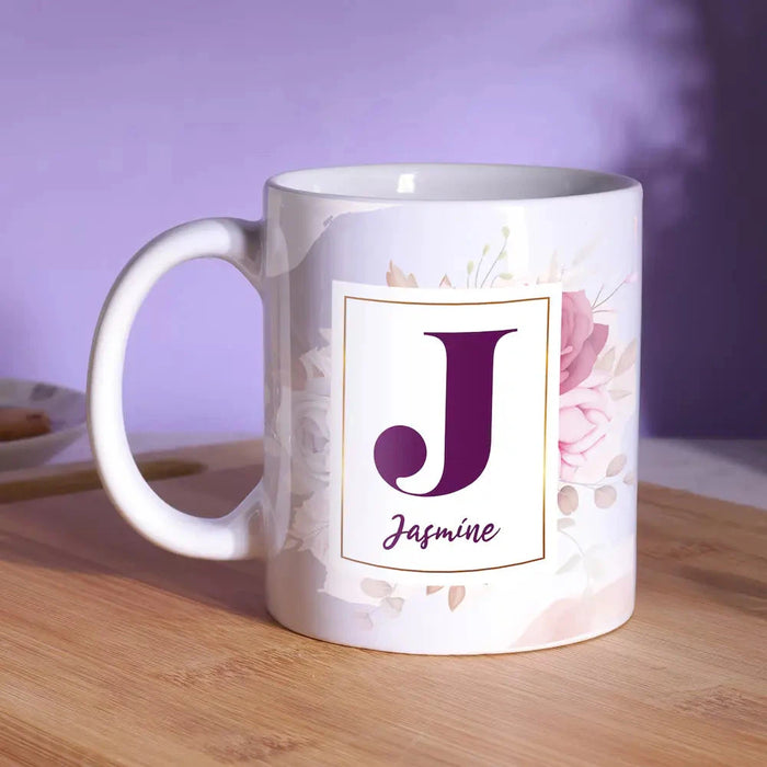 Personalized ceramic mug with purple initial 'J' and name Jasmine on a floral white background. Ideal custom drinkware for gifting and daily use.
